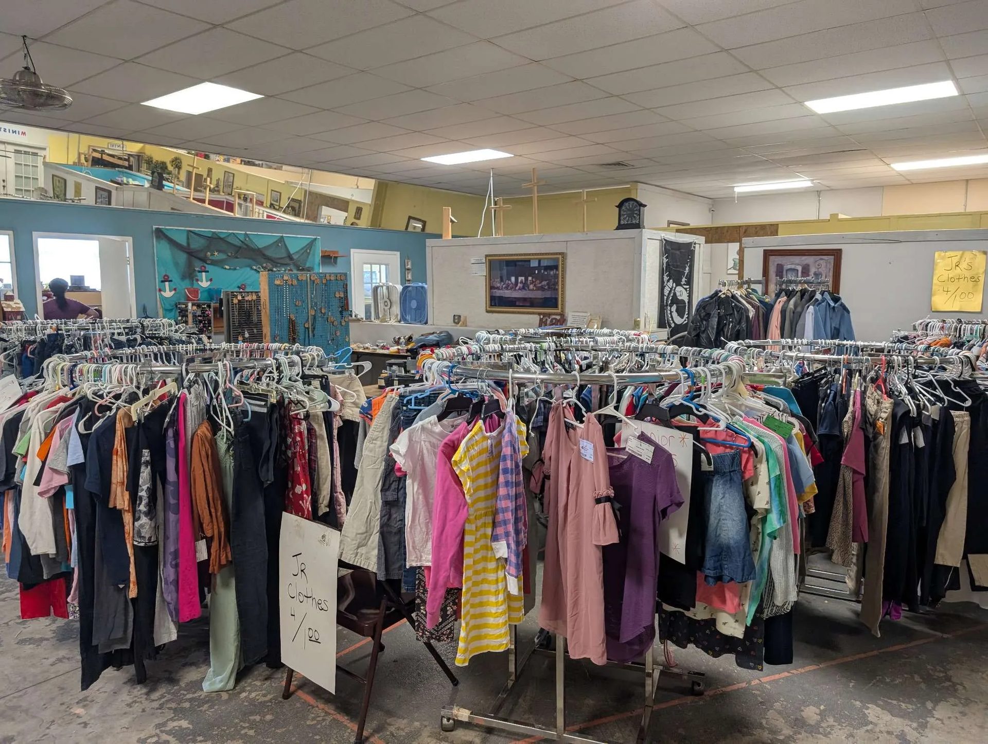 Inside the shop: aisles of clothing racks and hand-lettered price signs