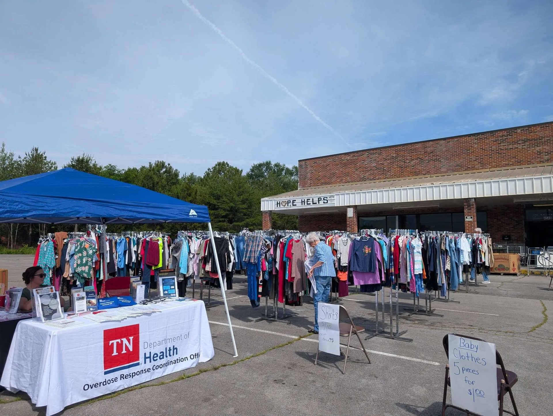 Yard sale in the car park in front of the HOPE HELPS storefront, with a community health stall